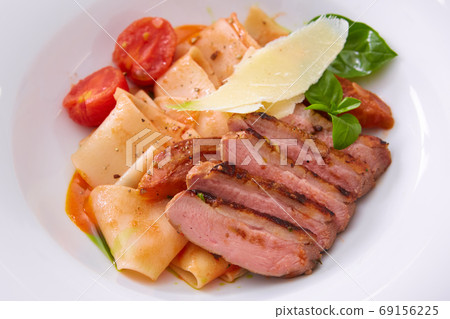 Close up view on cooked pasta and sliced duck breast with sauce and parmesan with copy space. Shallow dof. Close up view on cooked pasta and sliced duck breast with sauce and parmesan with copy space. Shallow dof. 69156225