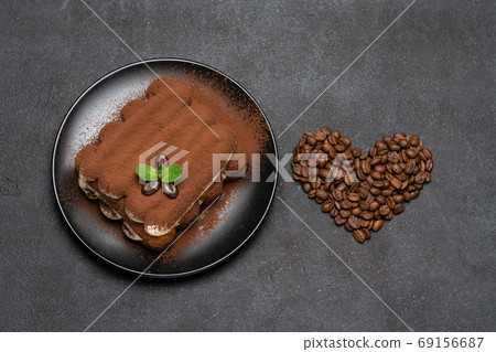 portion of Classic tiramisu dessert on ceramic plate and heart shaped coffee beans on concrete background 69156687