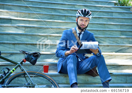 Businessman sitting on stairs and analyzes business report. Businessman sitting on stairs and analyzes business report. 69156719