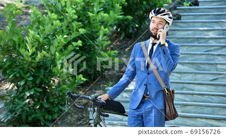 Businessman talking on smart phone with bicycle Businessman talking on smart phone with bicycle 69156726