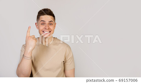Portrait of a cheerful guy pointing fingers up, showing number one Portrait of a cheerful guy pointing fingers up, showing number one 69157006