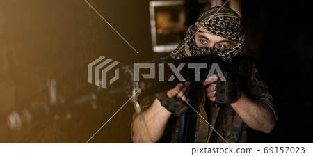 Arab male soldier in a headdress from the national keffiyeh with weapons in his hands. Muslim with 69157023