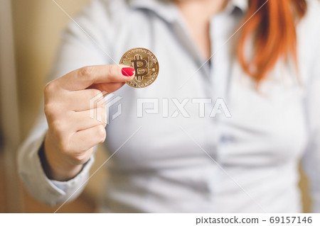 A woman holds a gold coin in her hands bitcoin 69157146