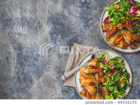 Roasted bbq wings with green salad with tomatoes. Top view 69158170
