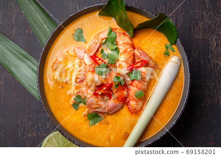 Shrimps Tom Yam Kung in grey bowl with thai spices on autentic tray top view, wooden background. Shrimps Tom Yam Kung in grey bowl with thai spices on autentic tray top view, wooden background. 69158201