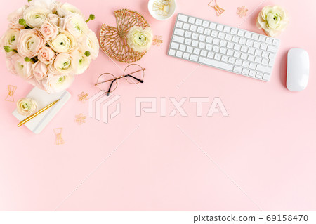 Stylized, pink women's home office desk. Workspace with computer, bouquet ranunculus and roses, clipboard on pink background. Flat lay. Top view. Stylized, pink women's home office desk. Workspace with computer, bouquet ranunculus and roses, clipboard on pink background. Flat lay. Top view. 69158470