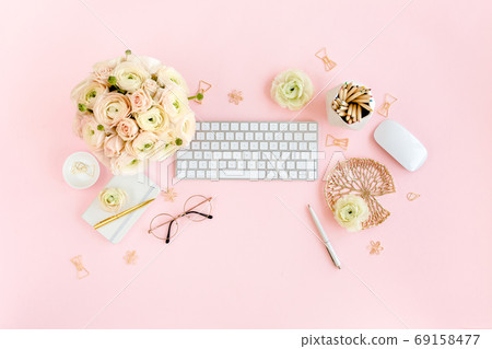 Stylized, pink women's home office desk. Workspace with computer, bouquet ranunculus and roses, clipboard on pink background. Flat lay. Top view. 69158477