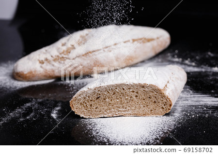 Gray bread sprinkled with flour. Homemade pastries, bread cut gavpil Gray bread sprinkled with flour. Homemade pastries, bread cut gavpil 69158702