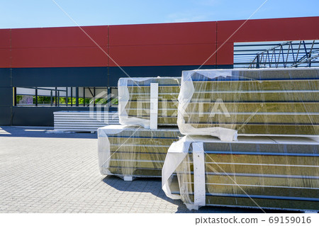 a pile of sandwich facade panels on the construction site of a new metal frame building a pile of sandwich facade panels on the construction site of a new metal frame building 69159016