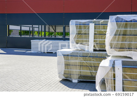 a pile of sandwich facade panels on the construction site of a new metal frame building 69159017