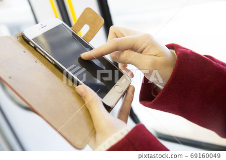 Woman looking at smartphone by train 69160049