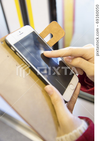 Woman looking at smartphone by train 69160050