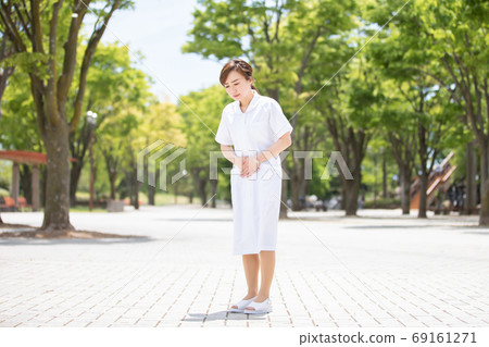Woman in white coat with stomachache 69161271