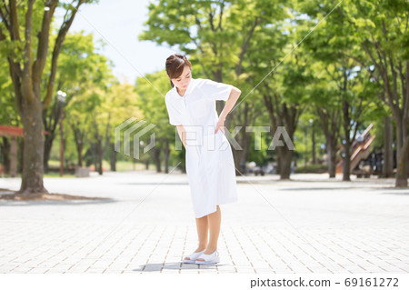 Woman in white coat with backache Woman in white coat with backache 69161272