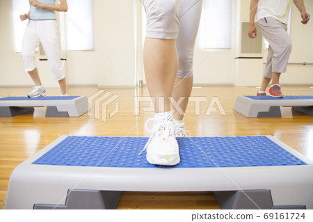 Men and women doing step exercises 69161724