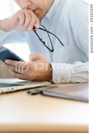 A middle man looking at a computer and a smartphone A middle man looking at a computer and a smartphone 69162889