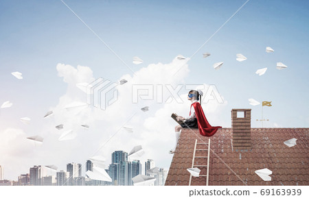 Girl power concept with cute kid guardian against cloudscape background. Mixed media Girl power concept with cute kid guardian against cloudscape background. Mixed media 69163939