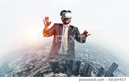 Handsome elegant businessman experiencing impressive virtual reality and business city at backdrop 69164437