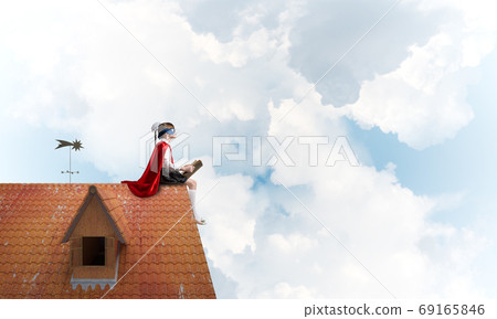 Girl power concept with cute kid guardian against cloudscape background. Mixed media 69165846