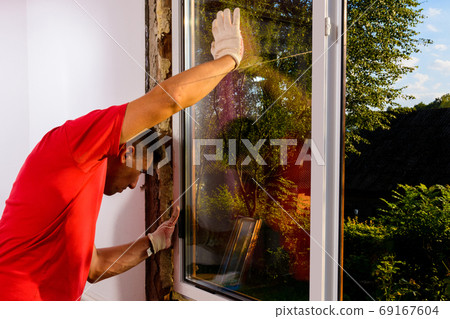 The worker inserts glass into the window frame, triple glazing of the plastic window, insulation and insulation. 69167604