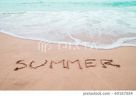 Summer word hand drawn on sand summer beach. 69167884