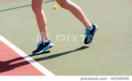 Legs of young girl in a closed tennis court with racket, sport shoes Legs of young girl in a closed tennis court with racket, sport shoes 69168048