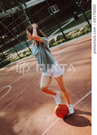 Young pretty woman posing on basketball court at sunset 69170000