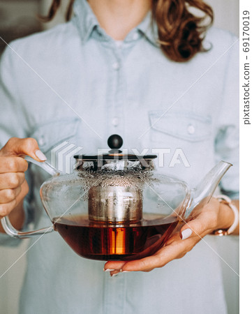 Young woman holding a glass teapot 69170019