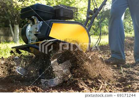 Close up view on fuzz soil nuggets during motor cultivator garden plow job 69171244