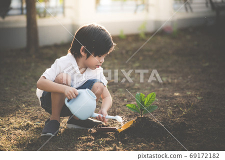 Cute Asian child watering young tree Cute Asian child watering young tree 69172182