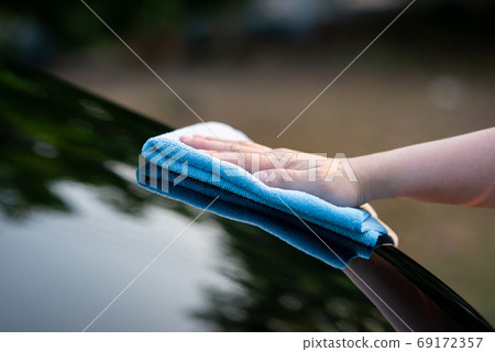 hand wiping water on black car 69172357