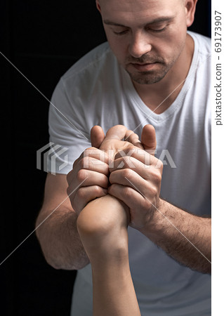 Male masseur hands doing reflexology massage on female foot reflex zones in the spa salon. 69173907