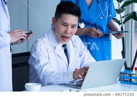 Doctor and medical assistants discussing about diagnosis result on laptop. Doctor and medical assistants discussing about diagnosis result on laptop. 69175150