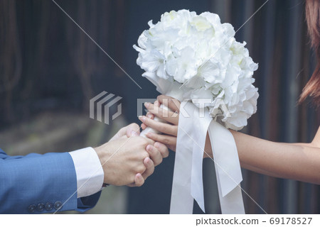 Caucasian handsome man giving flowers to asian girlfriend asking for proposing to marry  69178527