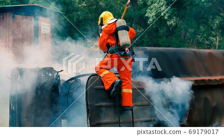 Firefighter fighting with flame using fire hose chemical water Firefighter fighting with flame using fire hose chemical water 69179017