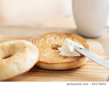 Spread cream cheese on toasted bagels 69179643