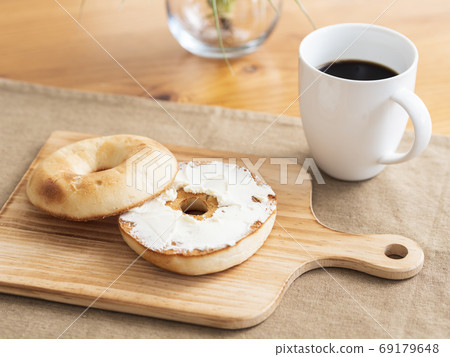 在烤百吉餅上塗奶油乾酪 在烤百吉餅上塗奶油乾酪 69179648