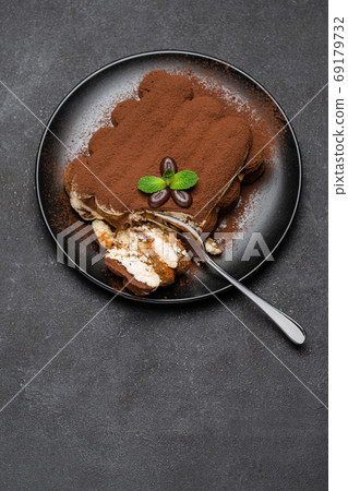 portion of Classic tiramisu dessert on ceramic plate on concrete background portion of Classic tiramisu dessert on ceramic plate on concrete background 69179732