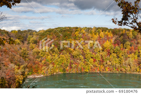 Niagara Whirlpool. The view across Niagara Whirlpool located on the Canadian and American border. In the background can be seen the colorful foliage of trees during the fall. Niagara Whirlpool. The view across Niagara Whirlpool located on the Canadian and American border. In the background can be seen the colorful foliage of trees during the fall. 69180476