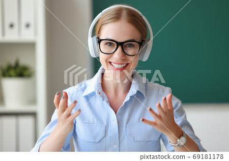 Friendly teacher in headphones looking at camera. 69181178