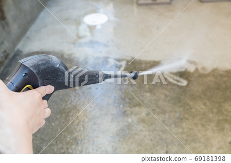 A scene where concrete is cleaned with a high pressure washer (focus on hand) 69181398