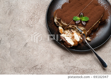 portion of Classic tiramisu dessert on ceramic plate on concrete background portion of Classic tiramisu dessert on ceramic plate on concrete background 69182047
