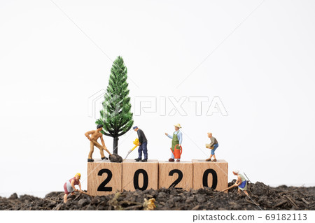 Gardeners  take care of a  tree on wooden block number 2020 69182113