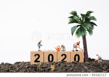 Gardeners  take care of a  tree on wooden block number 2020 69182117
