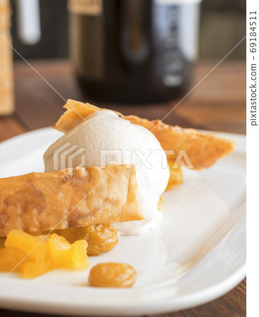 The ball of white vanilla ice cream with 2 waffles and mango fruit embellished with few raisins. The ball of white vanilla ice cream with 2 waffles and mango fruit embellished with few raisins. 69184511