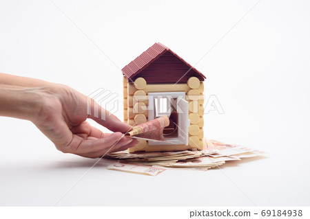 Hand puts a bill into the door of the toy house 69184938