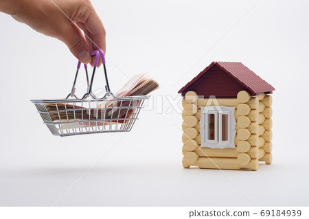 A hand brings a basket with a wad of money to the house 69184939