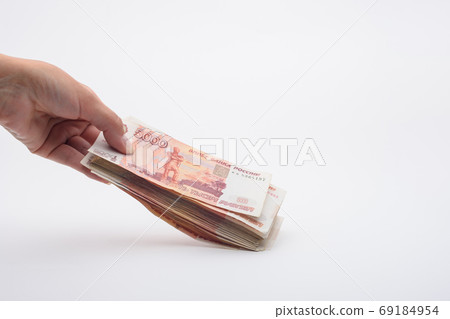 Hand holds out a bundle of five thousandth Russian banknotes 69184954