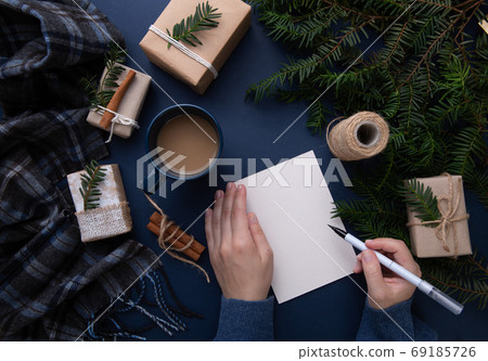 Hands hold a postcard and a pen on a background of blue steel with gifts Hands hold a postcard and a pen on a background of blue steel with gifts 69185726