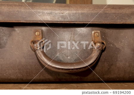 A rusty carry handle on an old brown leather suitcase 69194200